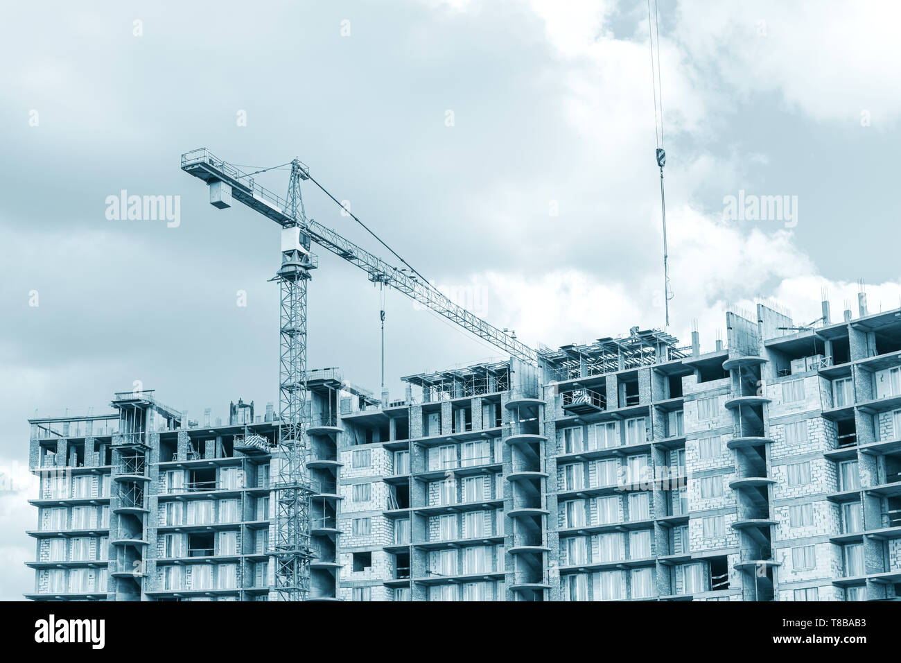 Costruzione di un nuovo edificio di appartamenti. gru a torre contro il cielo nuvoloso sfondo Foto Stock