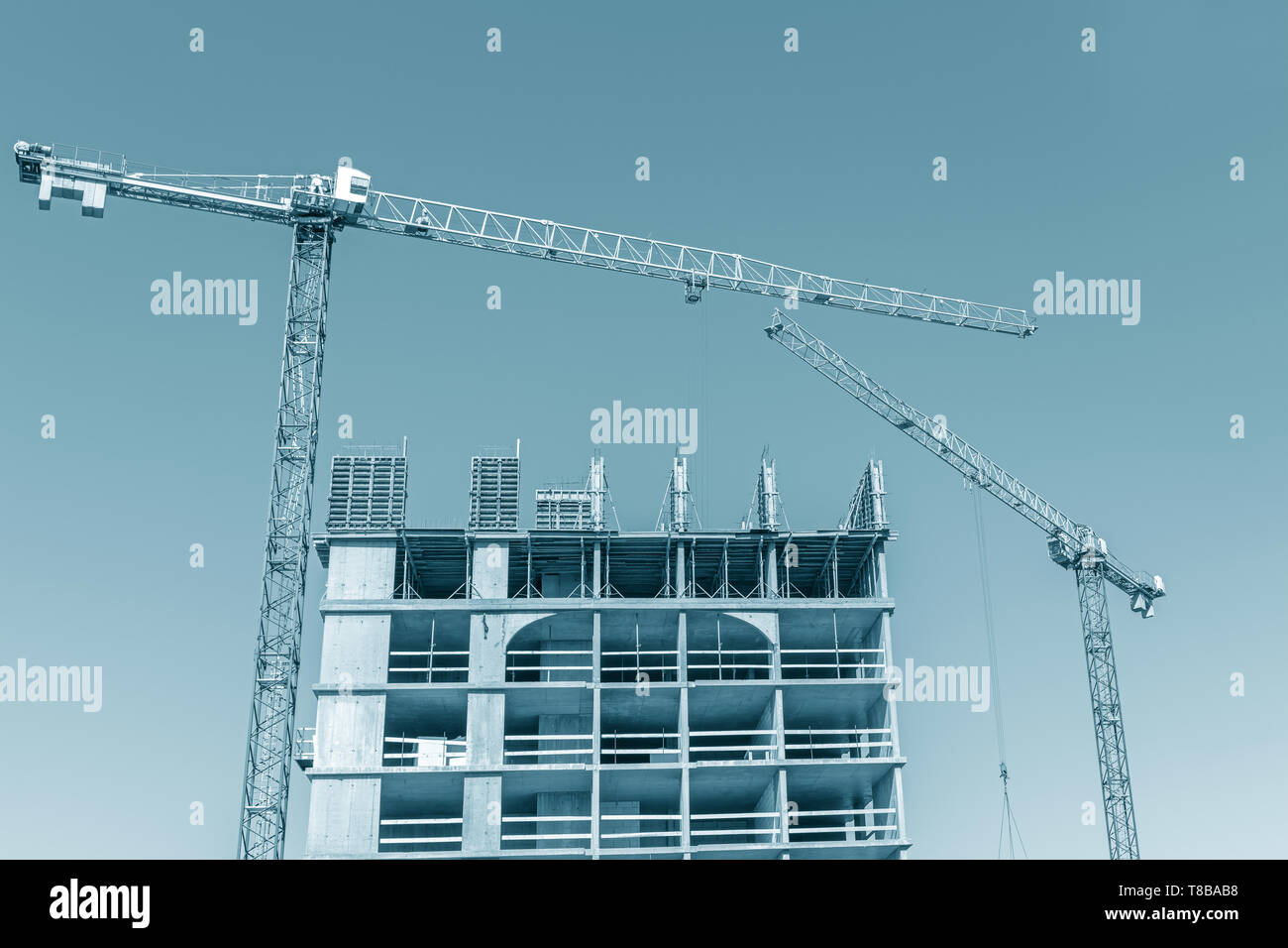 Un alto edificio in costruzione. sito di costruzione di gru contro il cielo blu Foto Stock