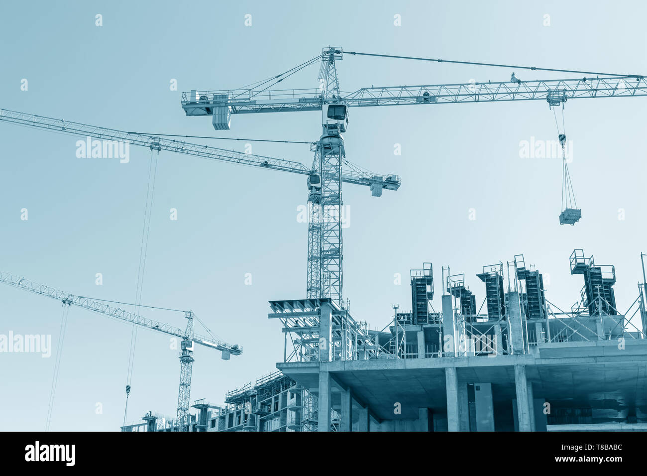 A più piani in calcestruzzo dell'edificio in costruzione. gru a torre sul sito in costruzione. immagine dai toni Foto Stock