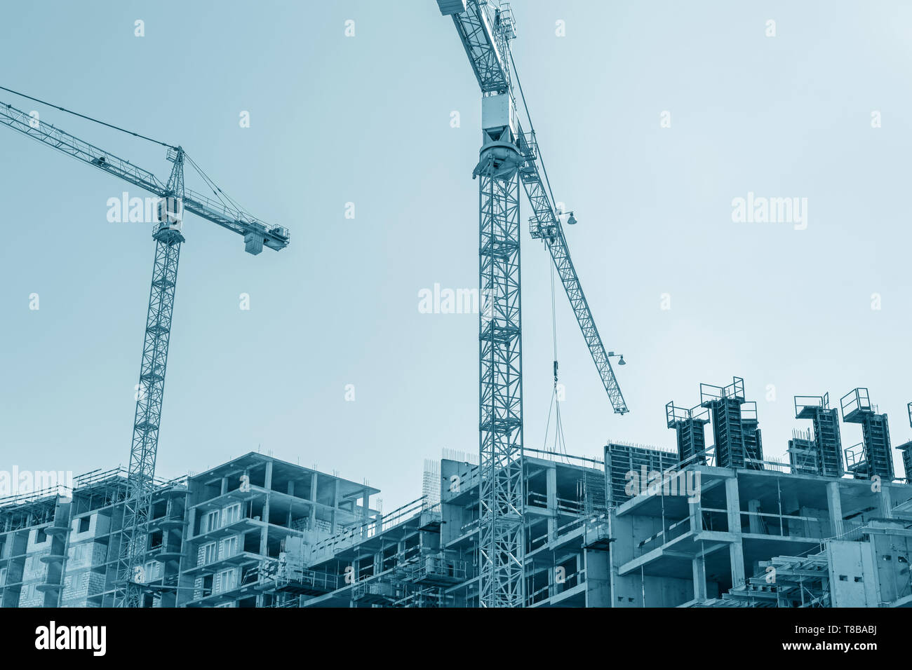 Città moderno edificio in costruzione e gru a torre contro il cielo blu sullo sfondo. vista dal basso Foto Stock