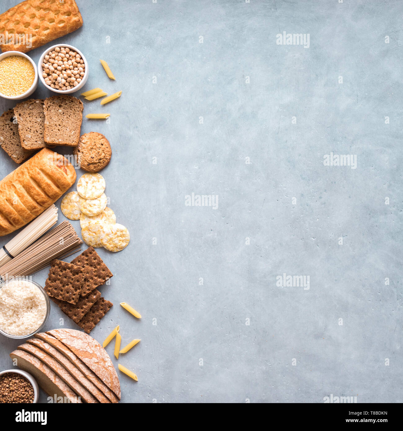 Prodotti senza glutine. Varie senza glutine pasta, pane, spuntini e farina su sfondo grigio chiaro, vista dall'alto, copia dello spazio. Foto Stock