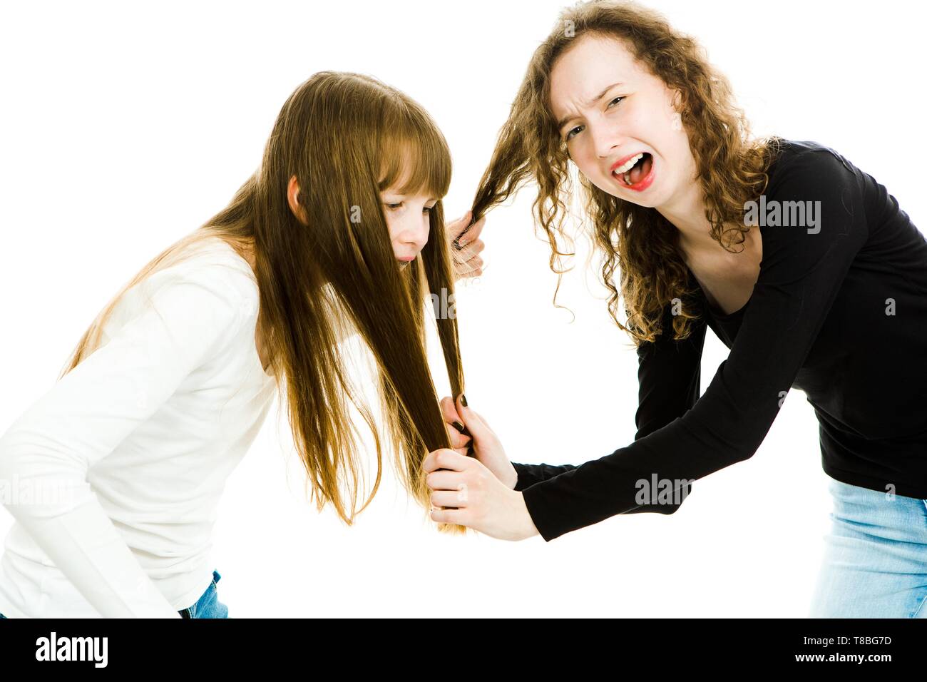 Una ragazza che abusa di altri tirando i suoi capelli. Paura e spaventata ragazza grida e urla, sorella di amore - sfondo bianco Foto Stock