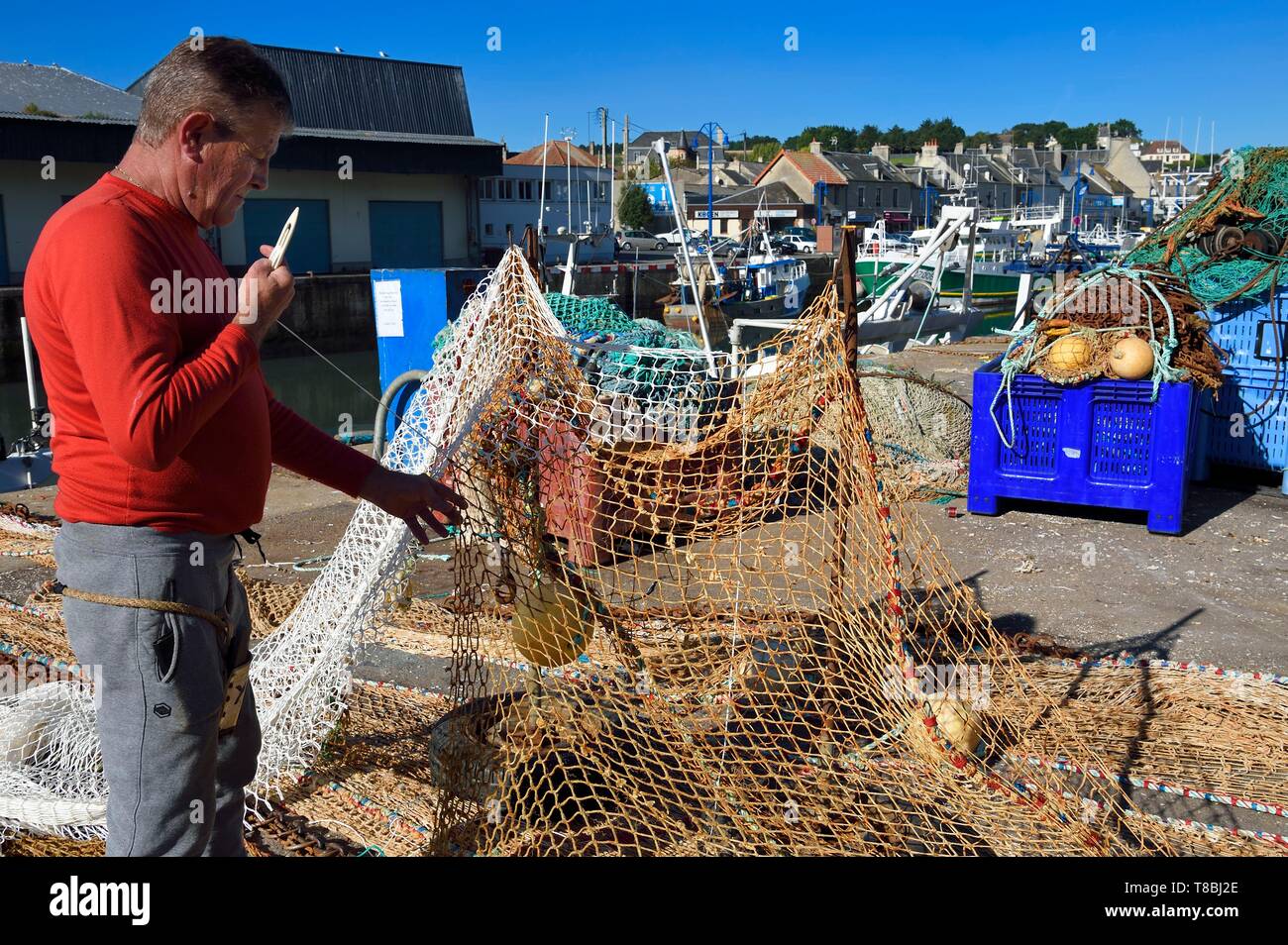 Francia, Calvados, Cote de Nacre, Port en bessin, il porto di pesca, fisherman riparazione di reti da pesca Foto Stock