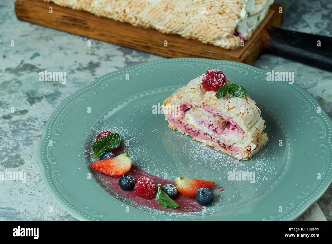 Torta di meringa roll fetta su un piatto di frutti di bosco Foto Stock