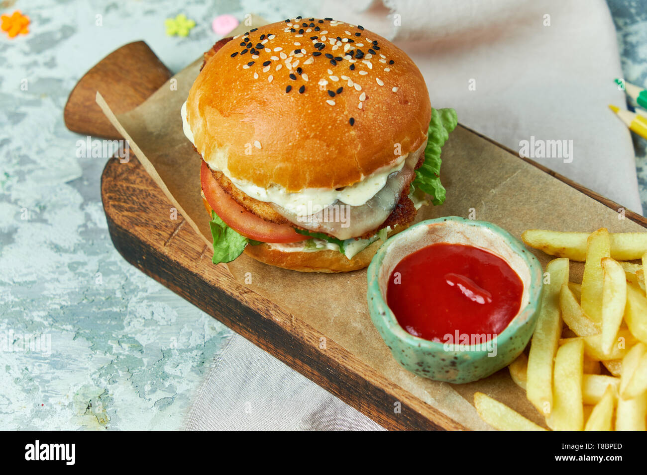 Formaggio hamburger. Con patatine fritte insalata di pomodori e maionese su una tabella di colore grigio e la tavola di legno Foto Stock