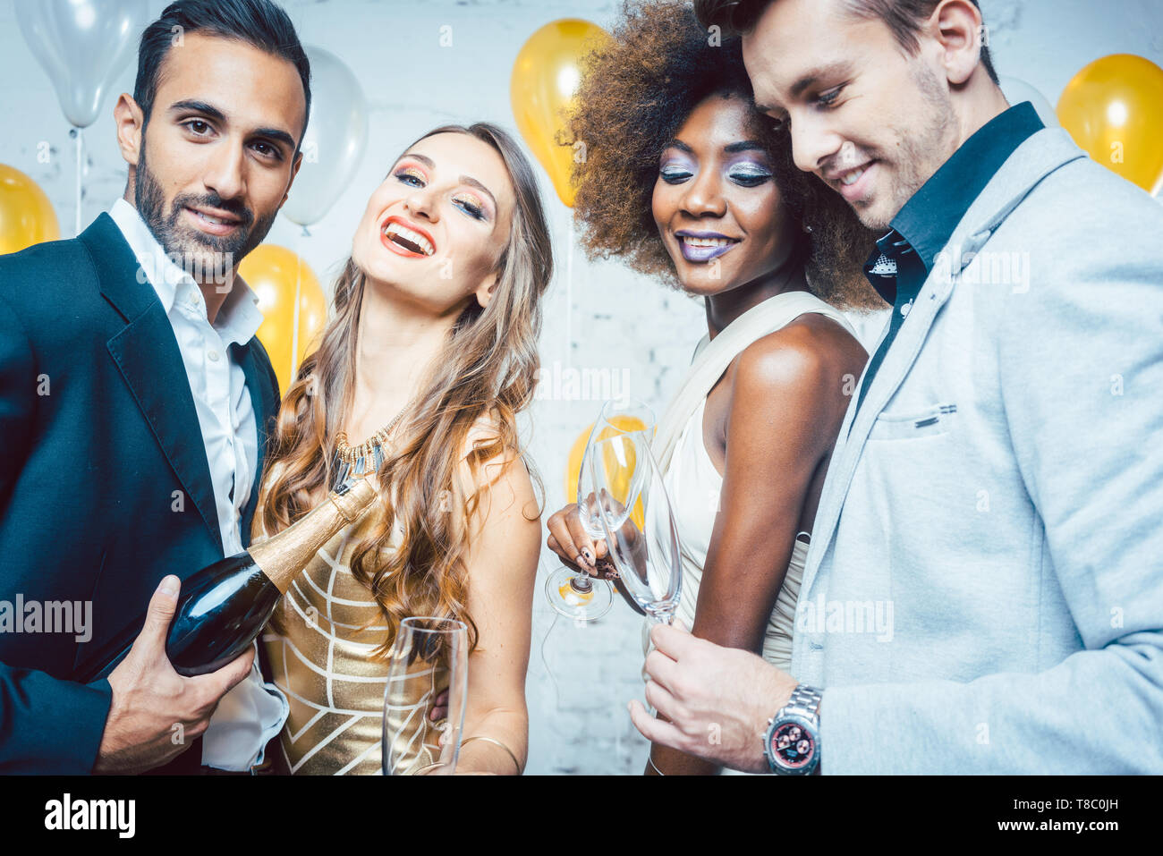 Partito popolare in un club che celebra e versando champagne Foto Stock