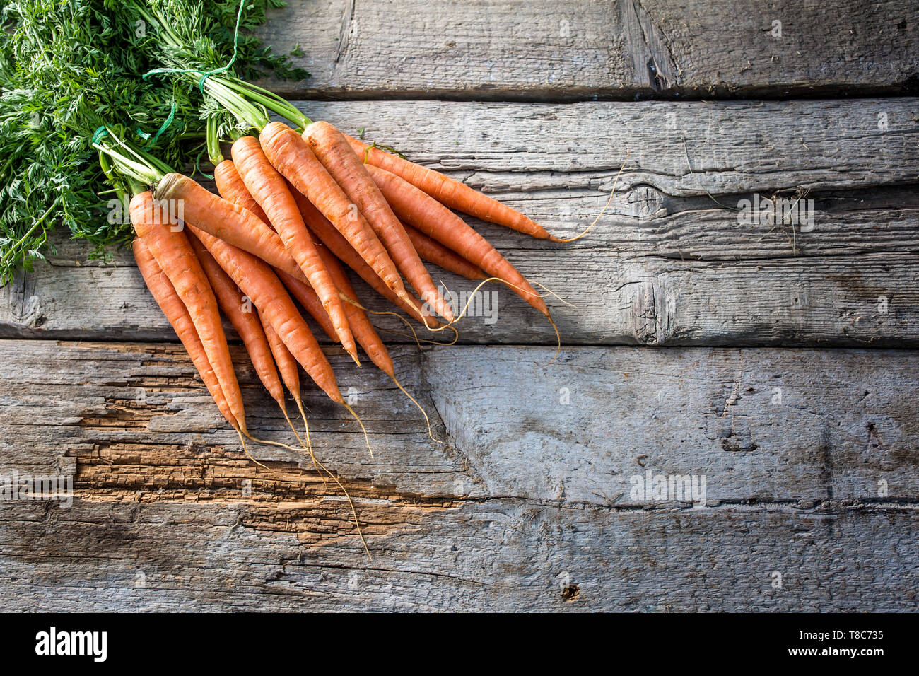 Mazzo di carote fresche liberamente giacente sul vecchio giardino board Foto Stock