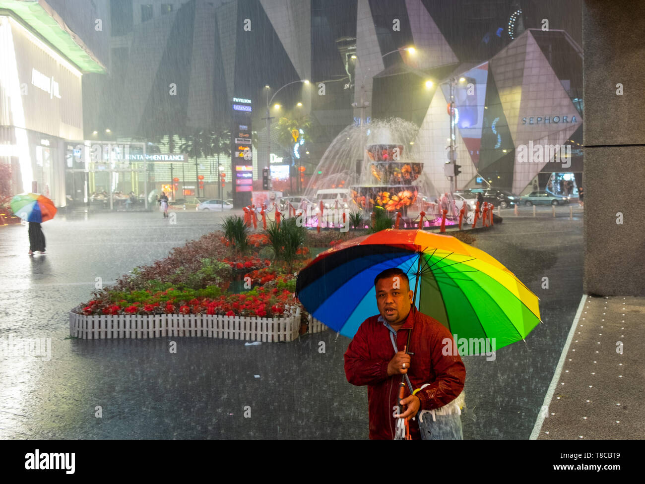 Ritratto di uomo vendita di ombrelloni su strada durante la doccia a pioggia di Kuala Lumpur in Malesia Foto Stock