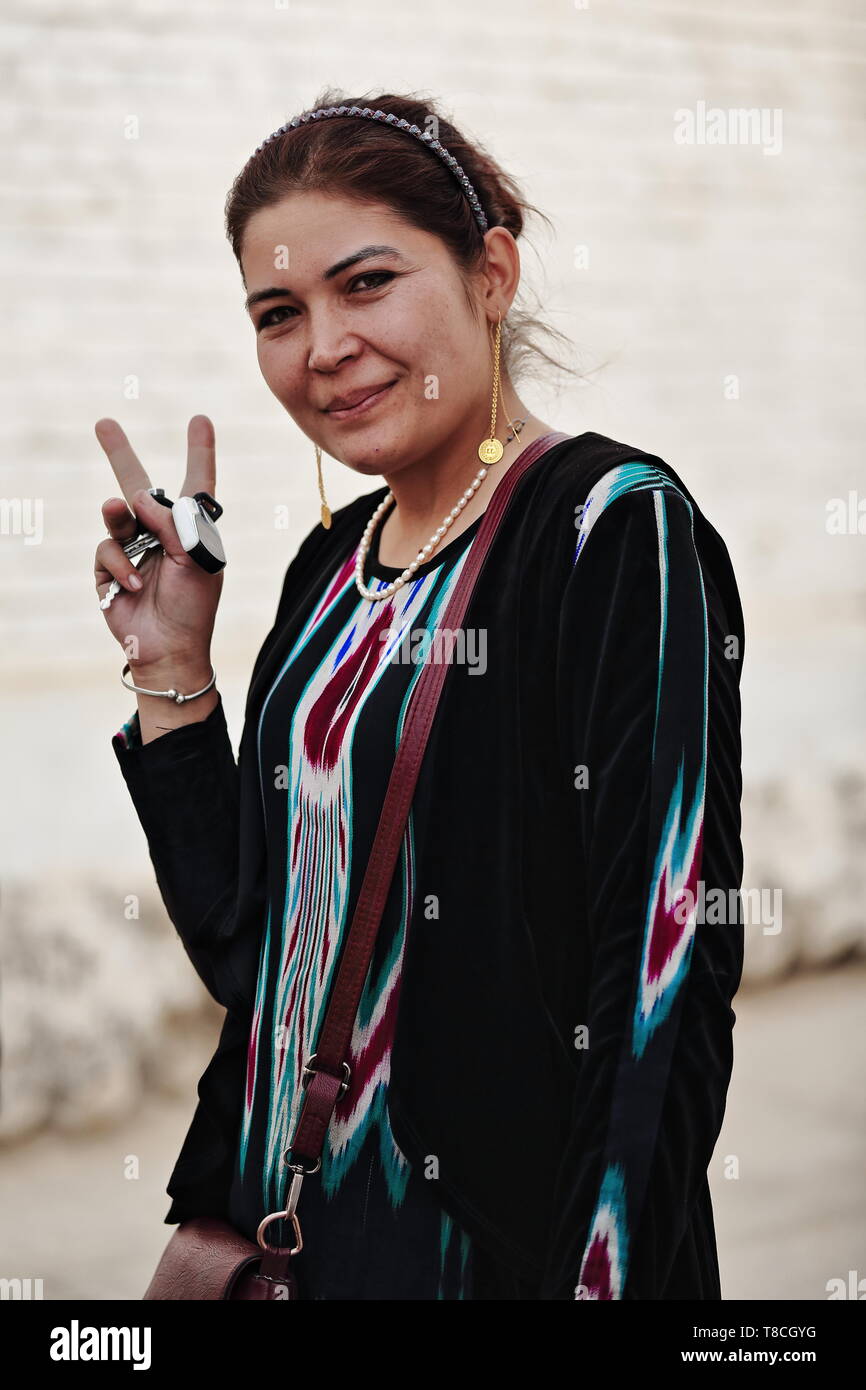 Uyghur donna in abbigliamento tradizionale-V segno n mano. Hotan-Xinjiang-Cina-0127 Foto Stock