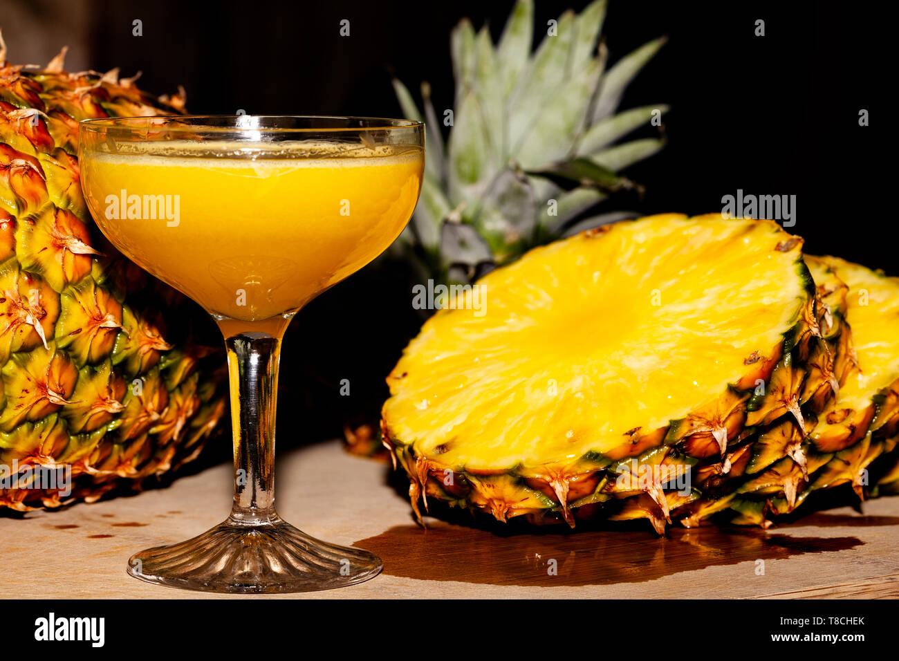 Un gustoso bicchiere di fresco, in casa di succo d'ananas circondato da una fresca ananas a fette Foto Stock