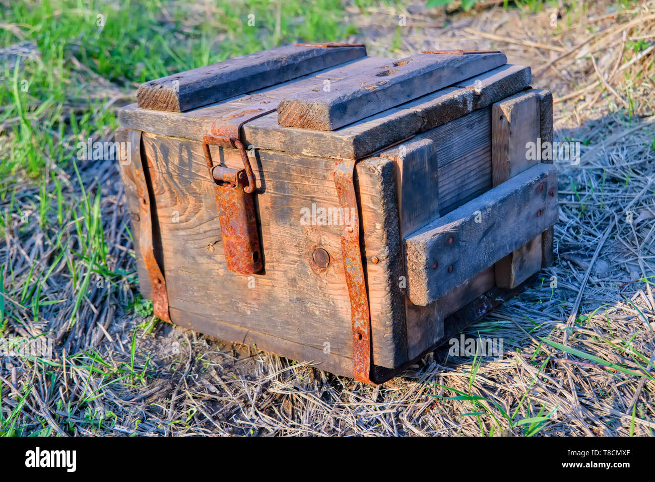Un antico scatola di legno con metallo arrugginito raccordi hardware poggia su un sfondo di erba di close-up. Foto Stock
