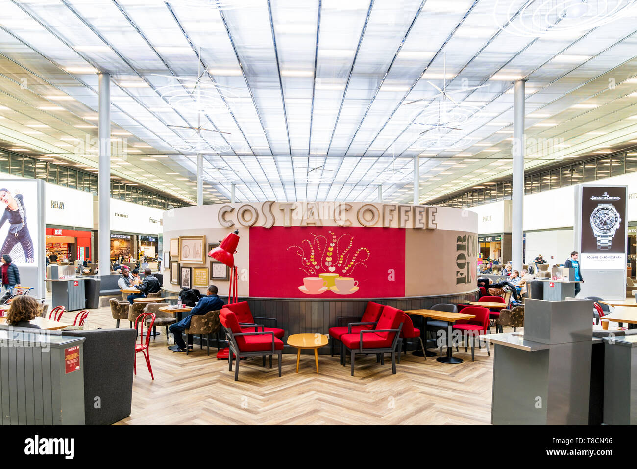 Dall'Aeroporto Charles De Gaulle di Parigi, Francia. Interno del Terminal 2E lounge di partenza. Le persone al caffè Costa aprire diner nell'area salotto centrale. Foto Stock