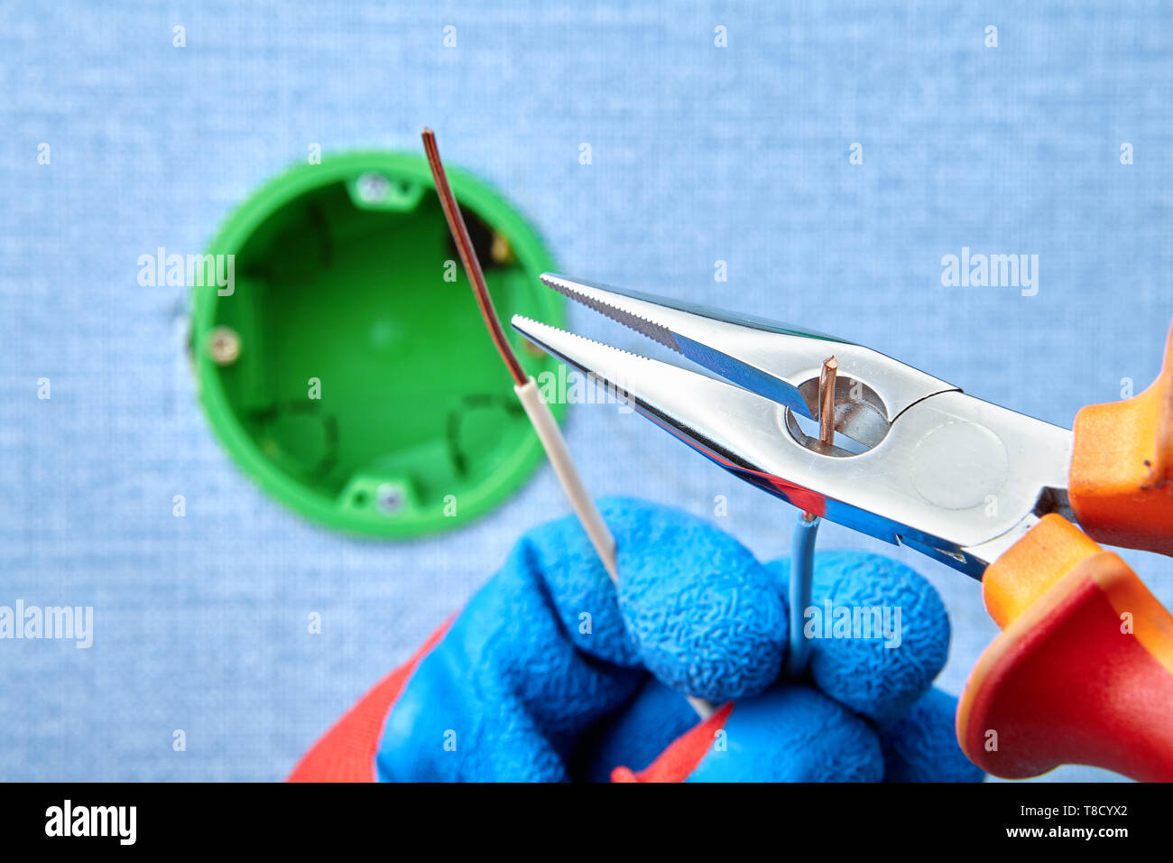 Installazione della presa rotonda box, fili di taglio con aiuto di pinze a becchi mezzotondi, manutenzione elettrica. Foto Stock