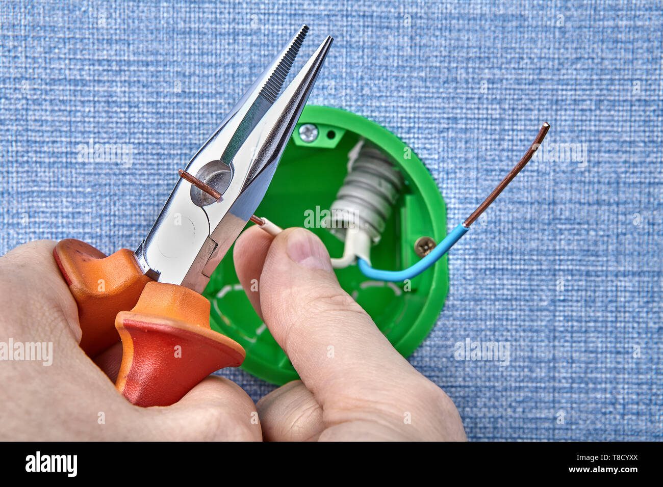 Elettricista è il montaggio del nuovo round della scatola elettrica il taglio di cavi in rame con pinze elettriche, lavori elettrici. Foto Stock