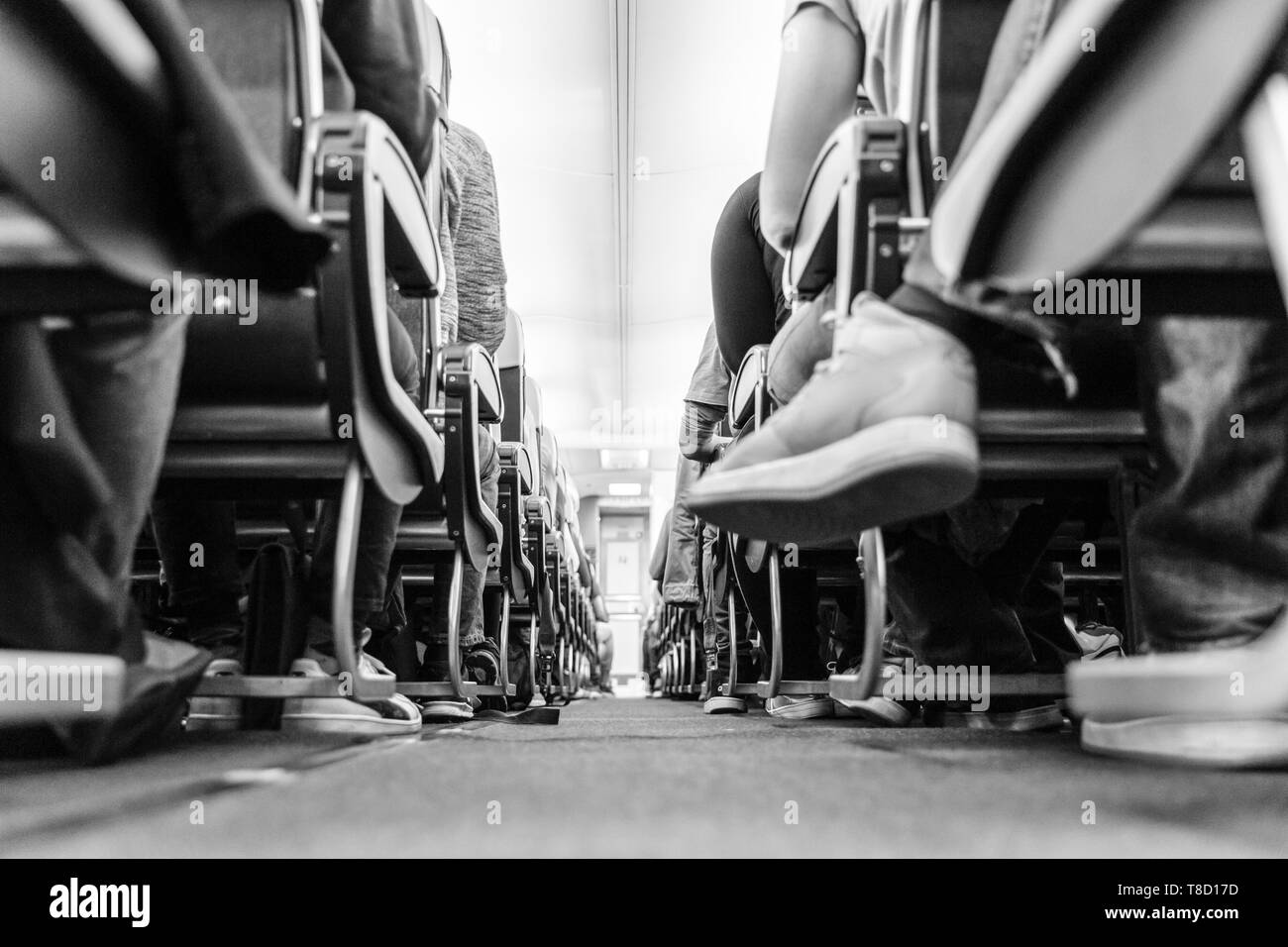 Bassa agle vista passenegers aereo commerciale corsia con passenegers seduti sulle loro sedi durante il volo. Foto in bianco e nero. Foto Stock