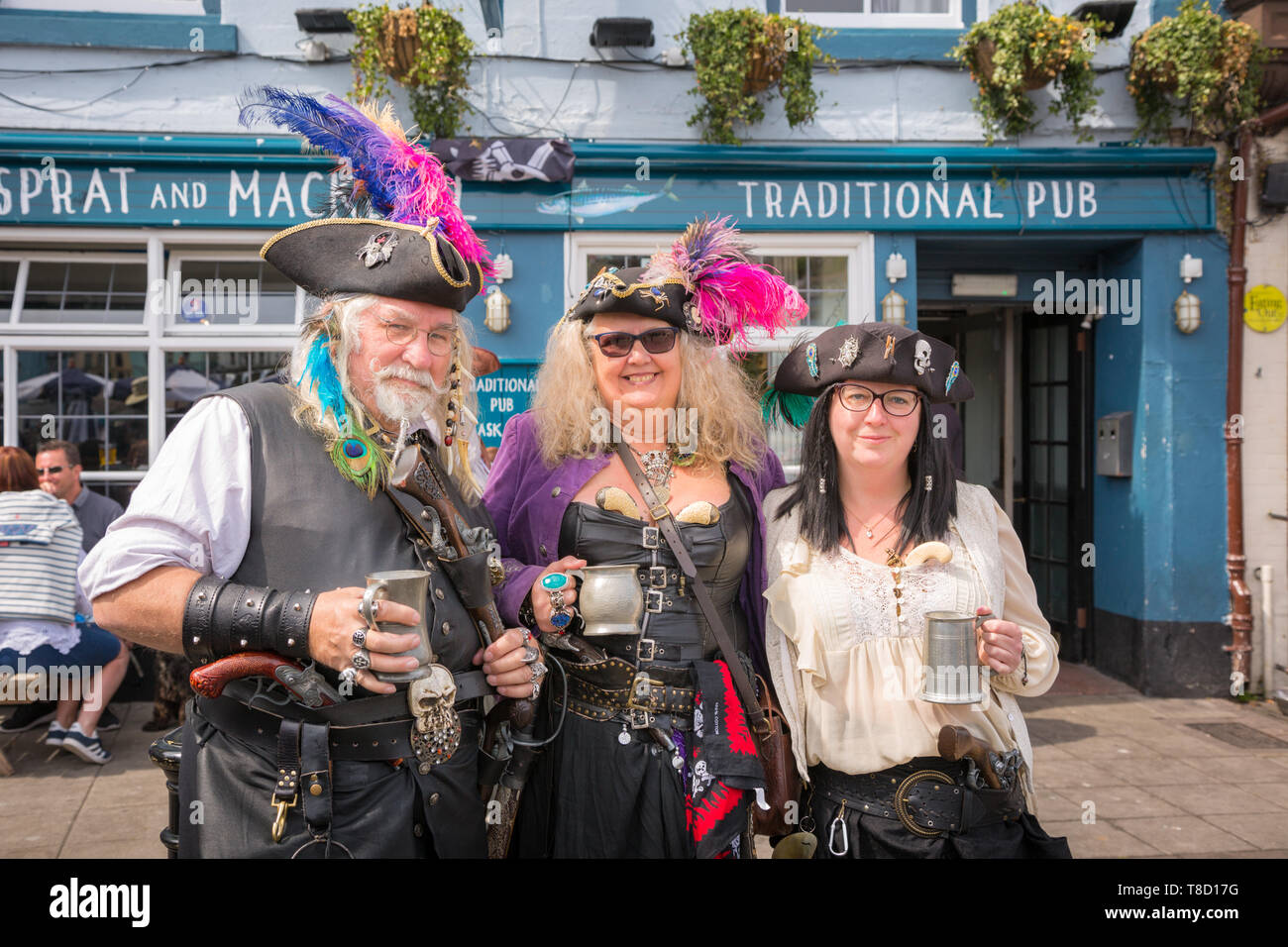 Tre persone vestite come pirati e bere in strada durante la Brixham pirate festival weekend, Devon, Regno Unito Foto Stock