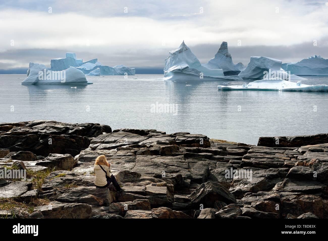 La Groenlandia, costa ovest, Disko Isola, Qeqertarsuaq village baia, escursionista sulle rocce e ghiacciai in background Foto Stock