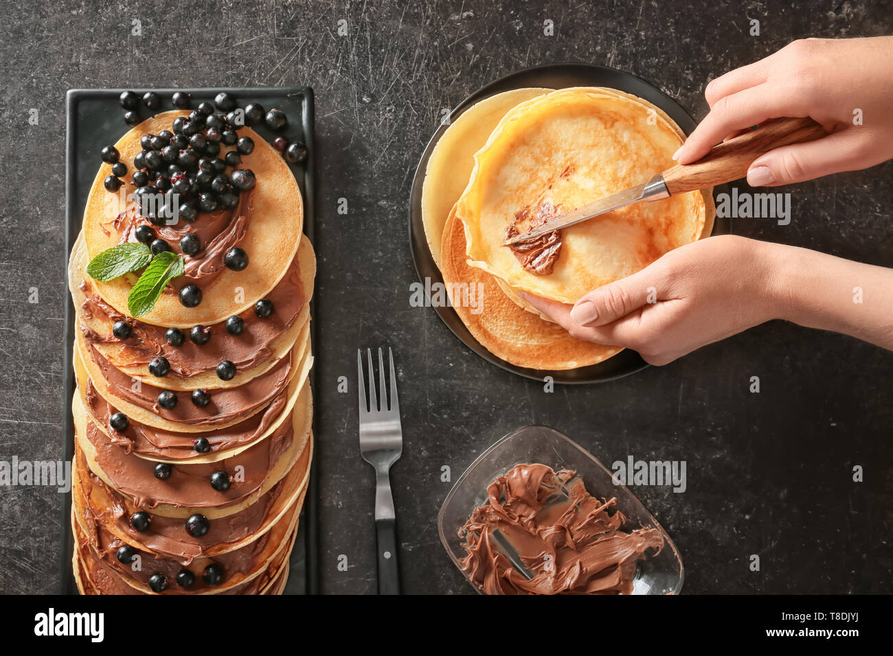 Macchiatura di donna pasta cioccolato sulle frittelle sottili Foto Stock