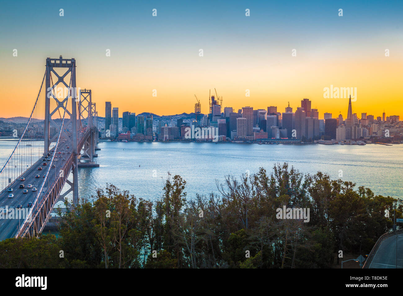 Classic vista panoramica del famoso Oakland Bay Bridge con lo skyline di San Francisco illuminato nel bellissimo tramonto con la luminosità del tramonto in estate, Ca Foto Stock