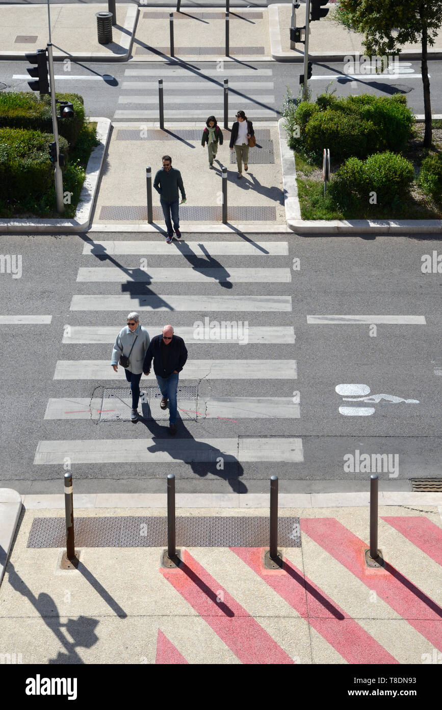 Vista aerea o ad alto angolo di visione di cinque pedoni che attraversano attraversamento pedonale o Zebra traversata Marsiglia Francia Foto Stock
