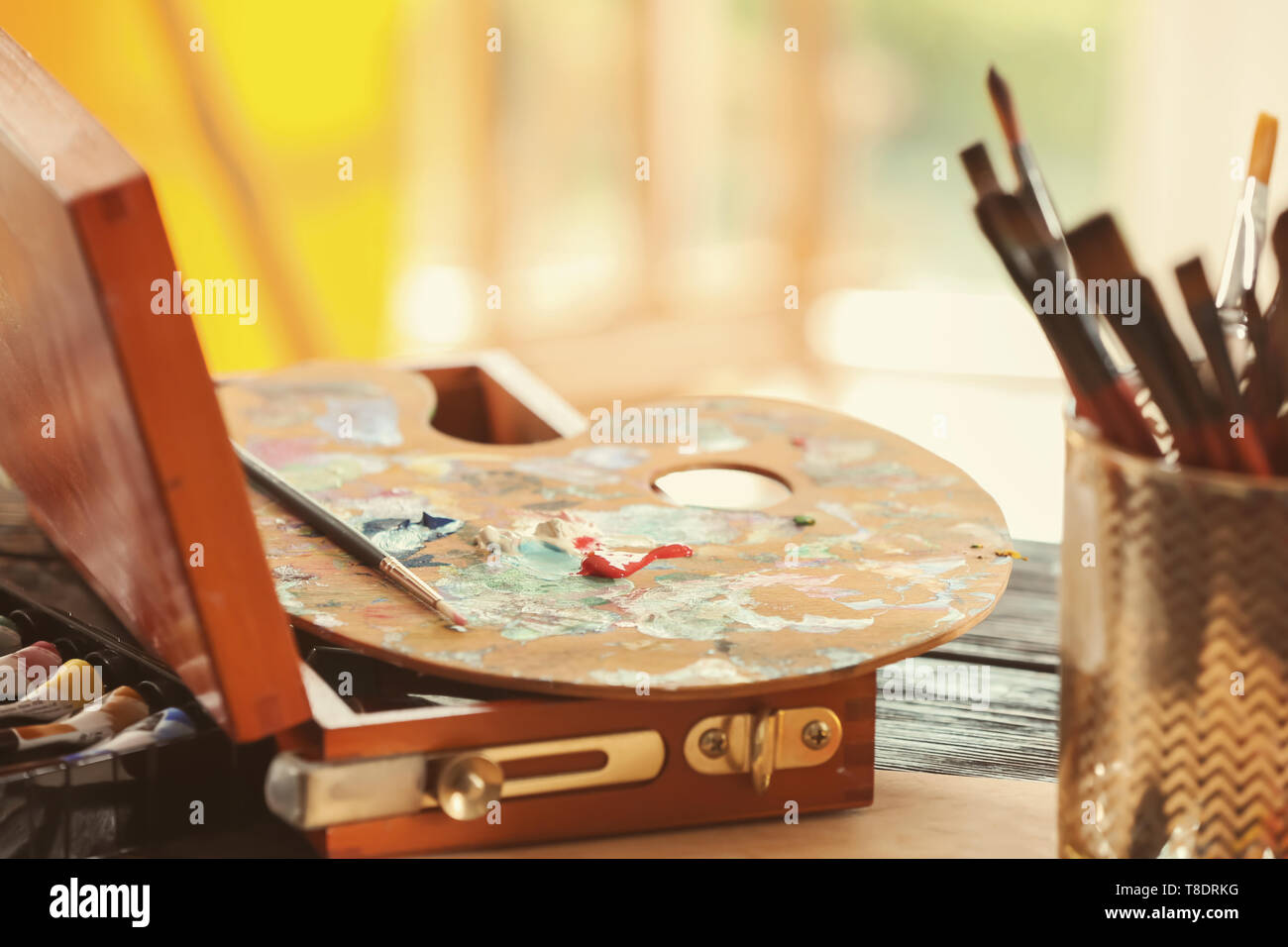Tavolozza di vernice con pennello sulla tavola in studio dell'artista Foto Stock