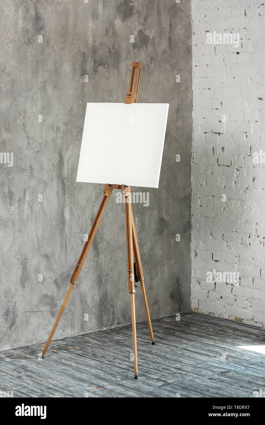 Cavalletto con tela vicino a parete in studio dell'artista Foto Stock