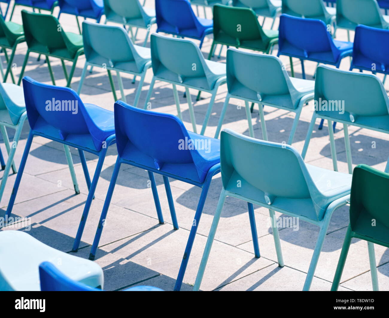Molti vuoti in plastica blu sedie all'aperto in una giornata di sole Foto Stock
