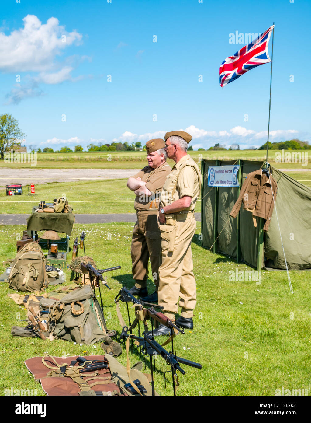 Il Museo del Volo, East Fortune, East Lothian, Scozia, Regno Unito il 12 maggio 2019. Esperienza di guerra: una giornata con la famiglia con tutte le cose relative al mondo di guerre. Gli uomini vestiti di seconda guerra mondiale di uniformi con un display di British equipaggiamento militare e un'Unione Jack flag Foto Stock