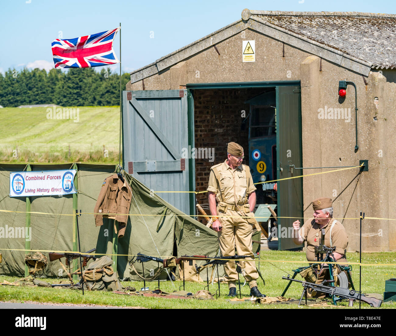 Il Museo del Volo, East Fortune, East Lothian, Scozia, Regno Unito il 12 maggio 2019. Esperienza di guerra: una giornata con la famiglia con tutte le cose relative al mondo di guerre. Gli uomini vestiti di seconda guerra mondiale di uniformi con un display di British equipaggiamento militare e un'Unione Jack flag Foto Stock