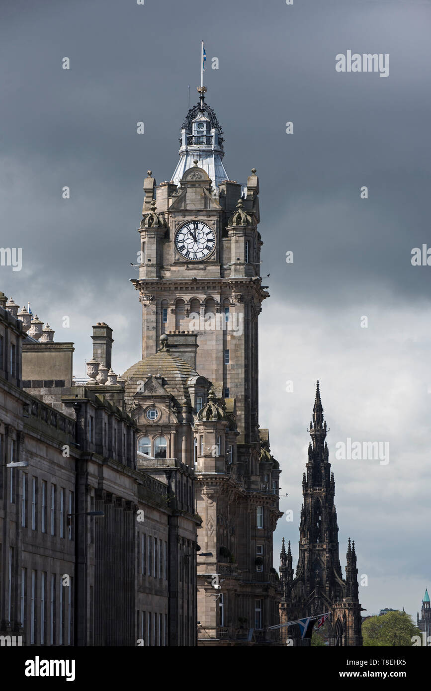 Il clocktower di The Balmoral Hotel su Princes Street con il Monumento di Scott dietro e un cielo minaccioso in lontananza, Edimburgo, Scozia, Regno Unito. Foto Stock