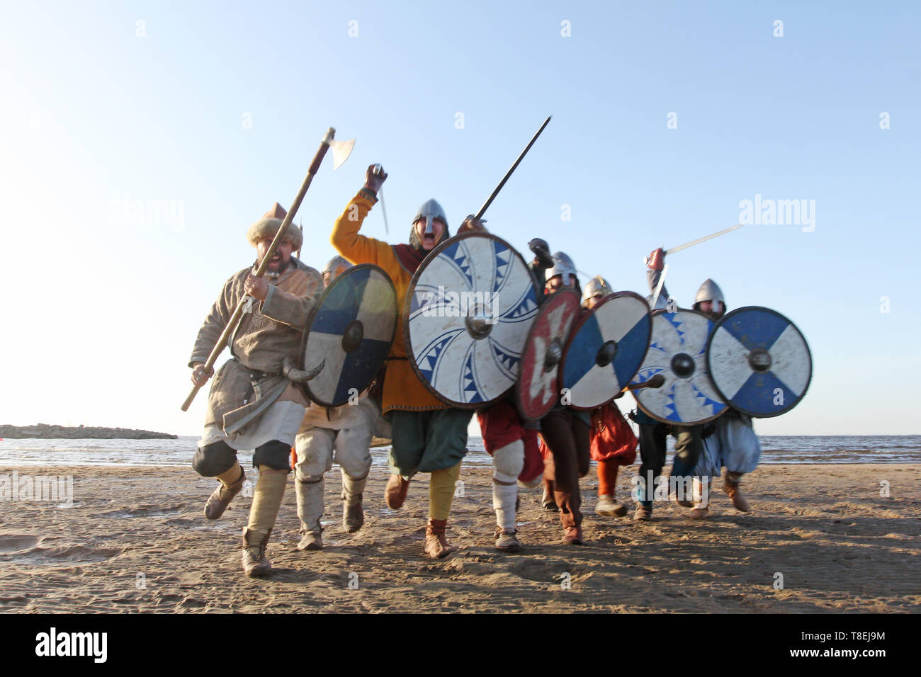 Guerrieri slavi reenactors con wearpons e protezioni formazione lotta all'aperto al mare , in esecuzione in telecamera Foto Stock