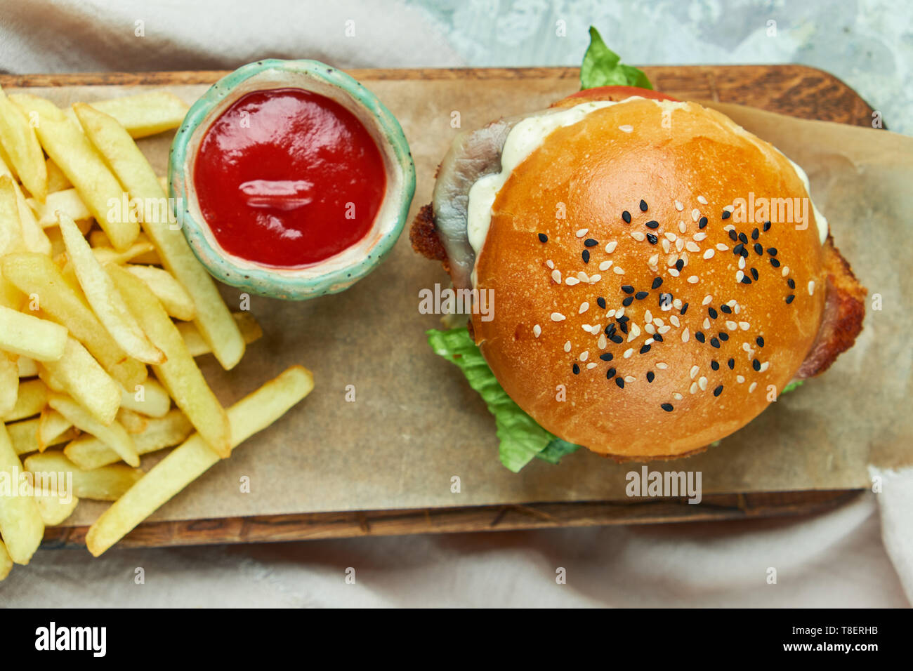 Formaggio hamburger. Con patatine fritte insalata di pomodori e maionese su una tabella di colore grigio e la tavola di legno Foto Stock