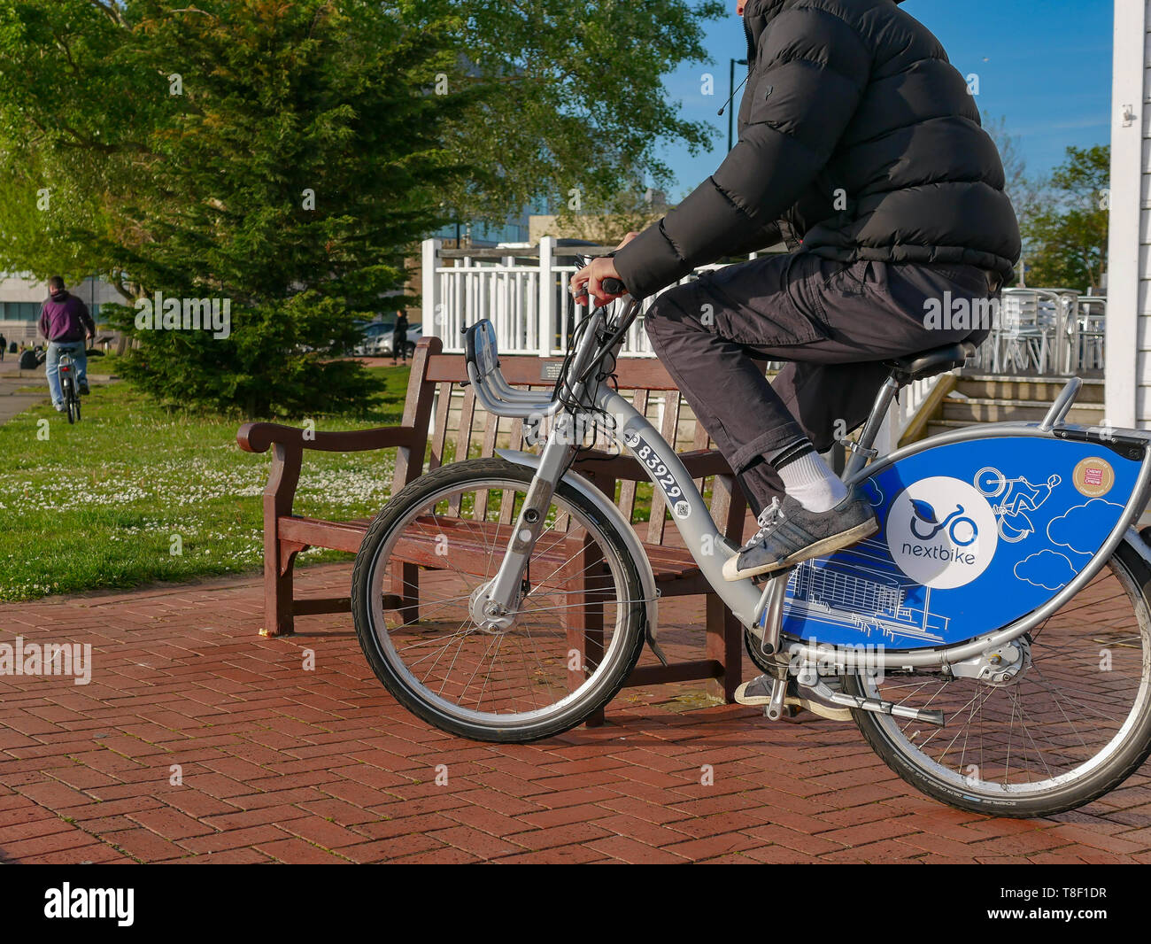 Pubblico di Cardiff Noleggio biciclette essendo utilizzato da giovani sulla strada a Cardiff Bay Foto Stock