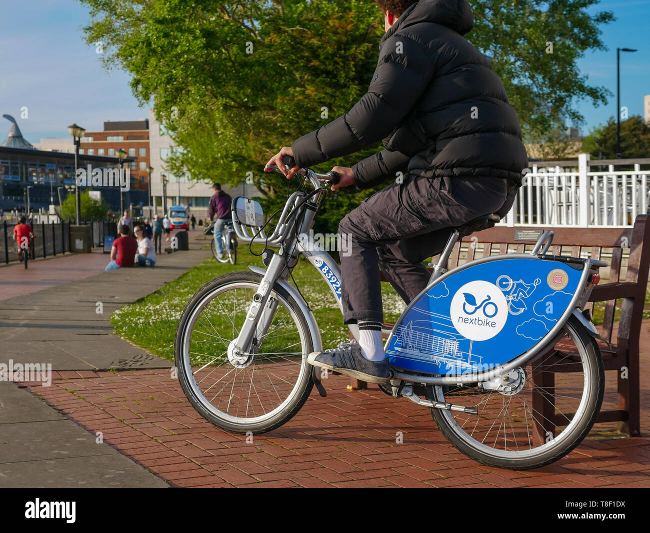 Pubblico di Cardiff Noleggio biciclette essendo utilizzato da giovani sulla strada a Cardiff Bay Foto Stock