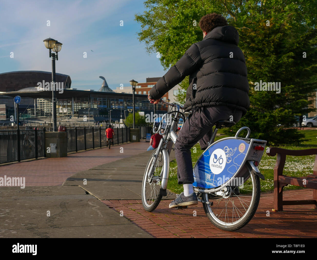 Pubblico di Cardiff Noleggio biciclette essendo utilizzato da giovani sulla strada a Cardiff Bay Foto Stock