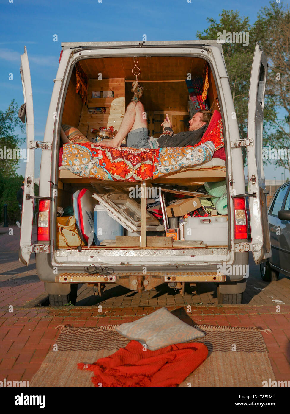 Alternative di vivere in città - un uomo si siede nel suo convertito home van nel centro della Baia di Cardiff Foto Stock