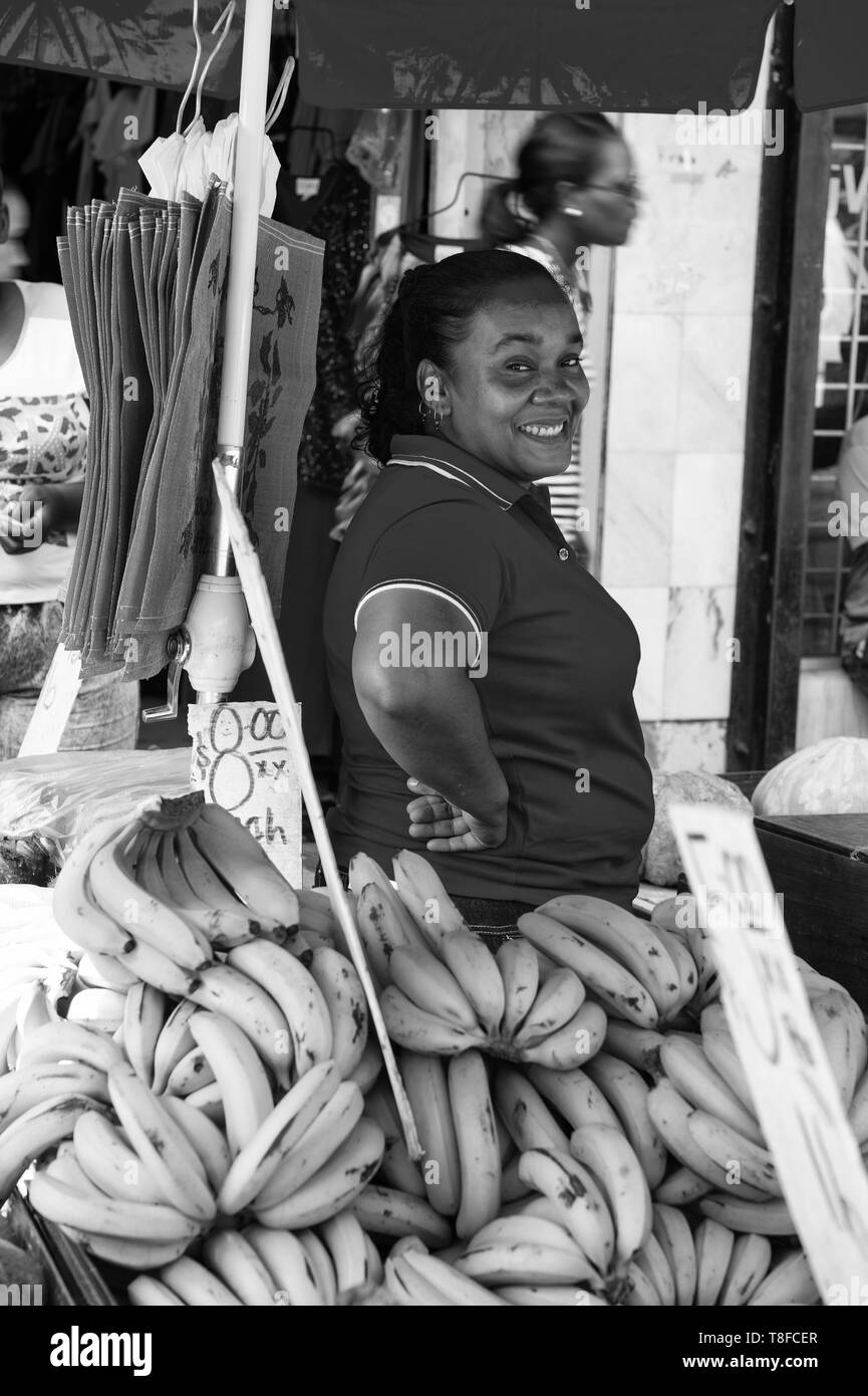 Porto di Spagna, Trinidad e Tobago - Novembre 28, 2015: Donna sorridente African American vende banane gialle di frutta sul locale mercato del sud outdoor Foto Stock