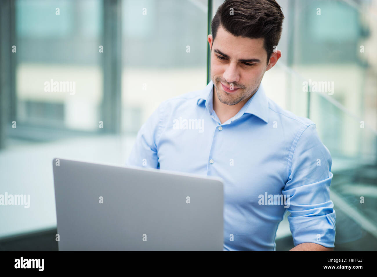 Un Ritratto di giovane imprenditore con seduta del notebook in ufficio. Foto Stock