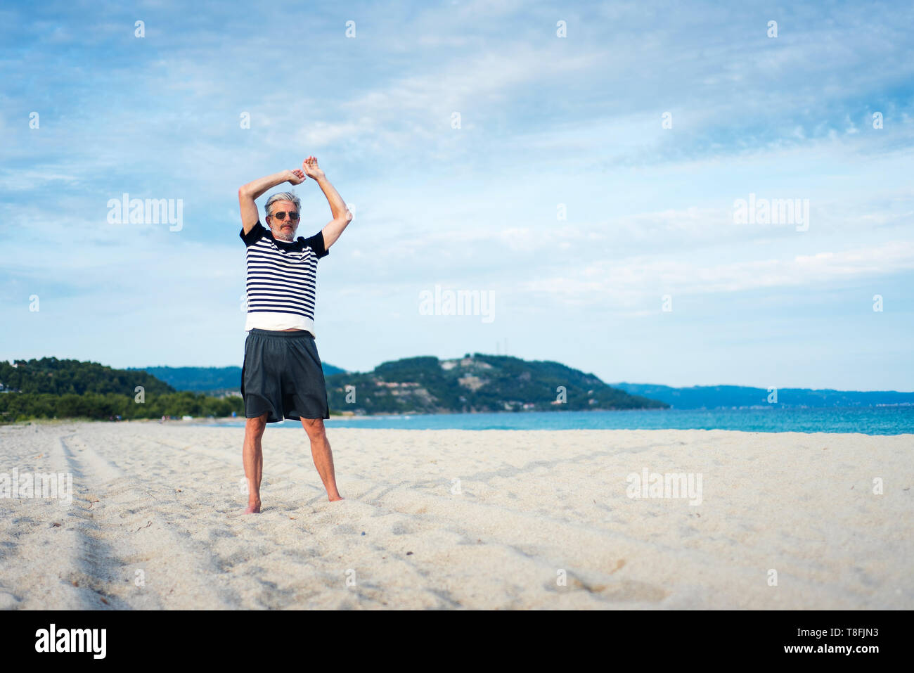 Senior uomo facendo esercizi di stretching sulla spiaggia, sport abstract Foto Stock