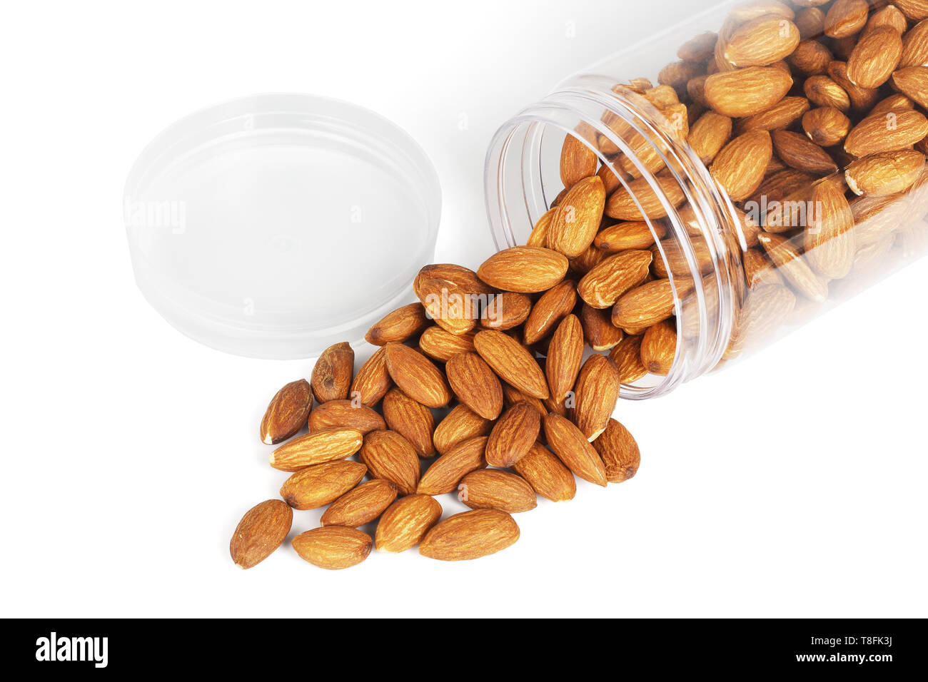 I dadi di mandorla versato fuori dal contenitore in plastica su sfondo bianco Foto Stock I dadi di mandorla versato fuori dal contenitore in plastica su sfondo bianco Foto Stock