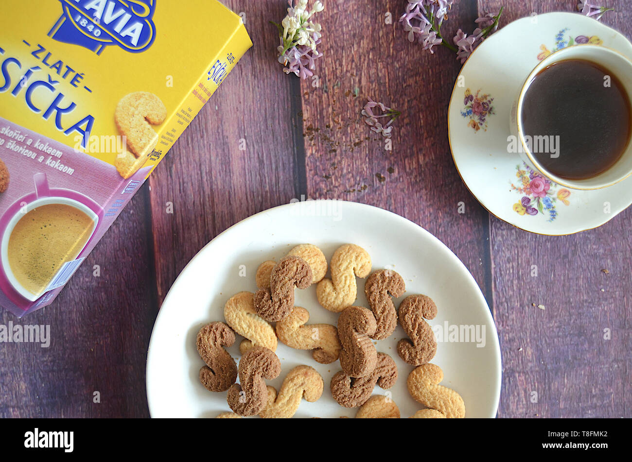 Ceca tradizionale cannella & cacao Biscotti Esicka su una piastra su un tavolo lungo con l'imballaggio originale scatola, un vecchio-fashionned tazza di tè e lilla Foto Stock