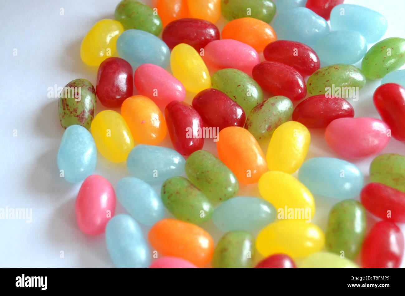 Un assortimento di dolce e salato colorato Jelly Beans caramelle con diversi sapori di frutta, giacente su una superficie bianca Foto Stock