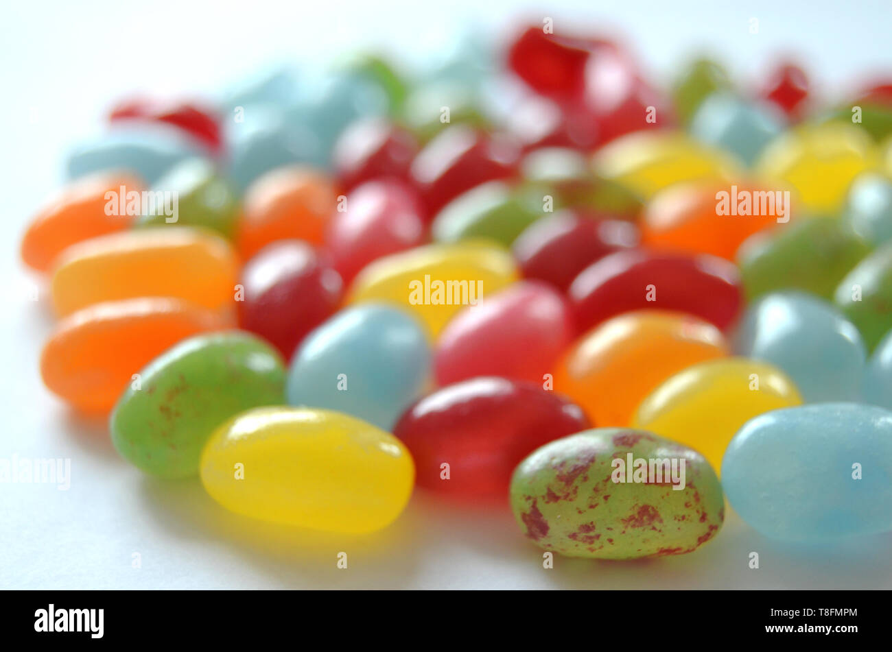 Un assortimento di dolce e salato colorato Jelly Beans caramelle con diversi sapori di frutta, giacente su una superficie bianca Foto Stock