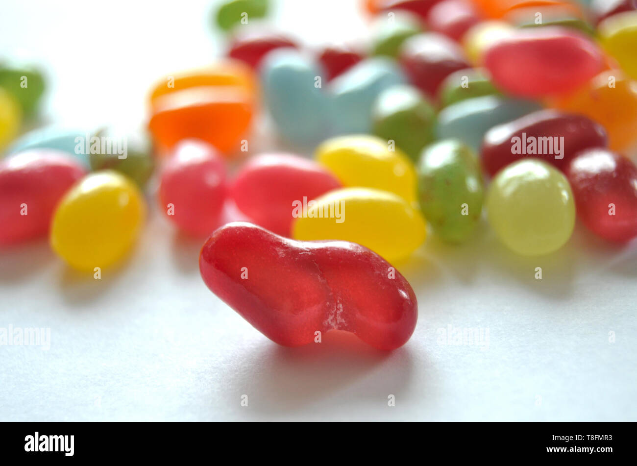 Un assortimento di dolce e salato colorato Jelly Beans caramelle con diversi sapori di frutta, giacente su una superficie bianca Foto Stock