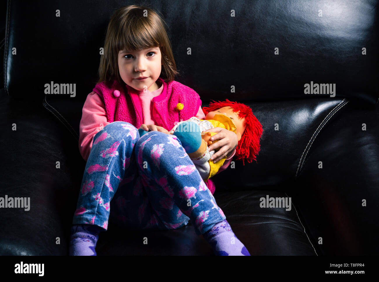 Carina ragazza con il suo giocattolo sul divano di casa Foto Stock