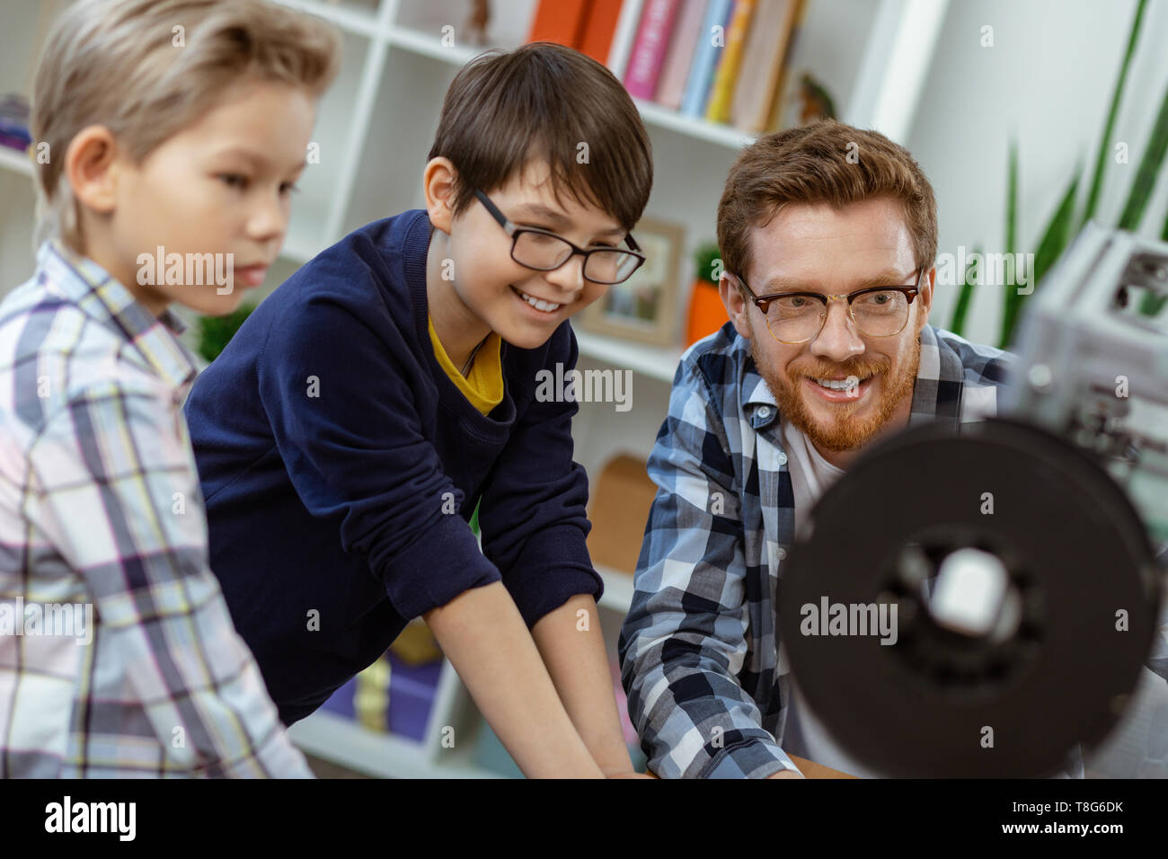 Piacevole insegnante ispirato presentando il suo meccanismo di studenti di 3d-stampante Foto Stock