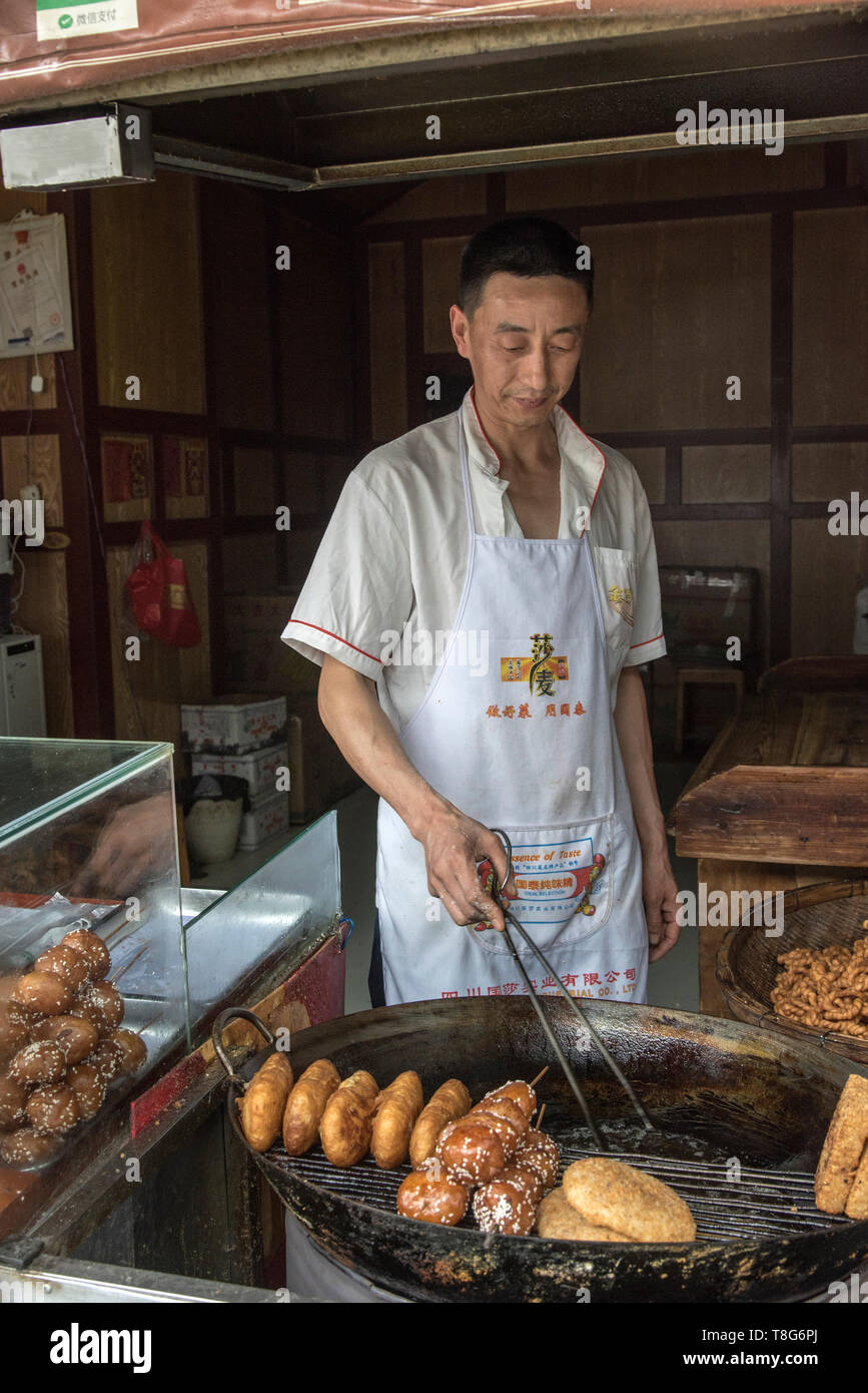 Cinese il cibo di strada. Cibo distributore vende prodotti alimentari in una fase di stallo nel Sichuan, in Cina Foto Stock