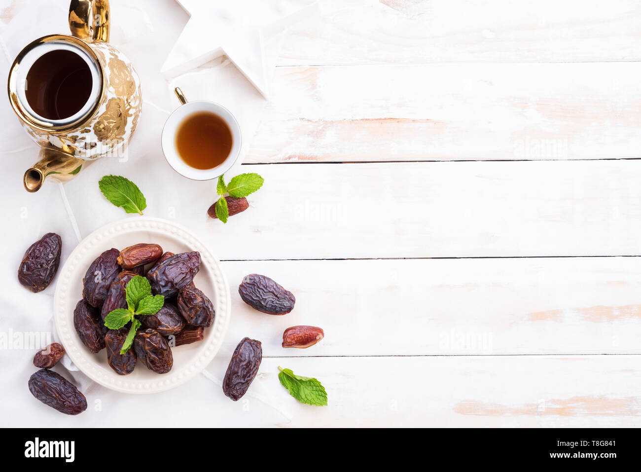 Il Ramadan il cibo e le bevande del concetto. Tè con date di frutta e foglie di menta su un di legno bianco sullo sfondo della tabella. Vista superiore, piatto laici. Foto Stock