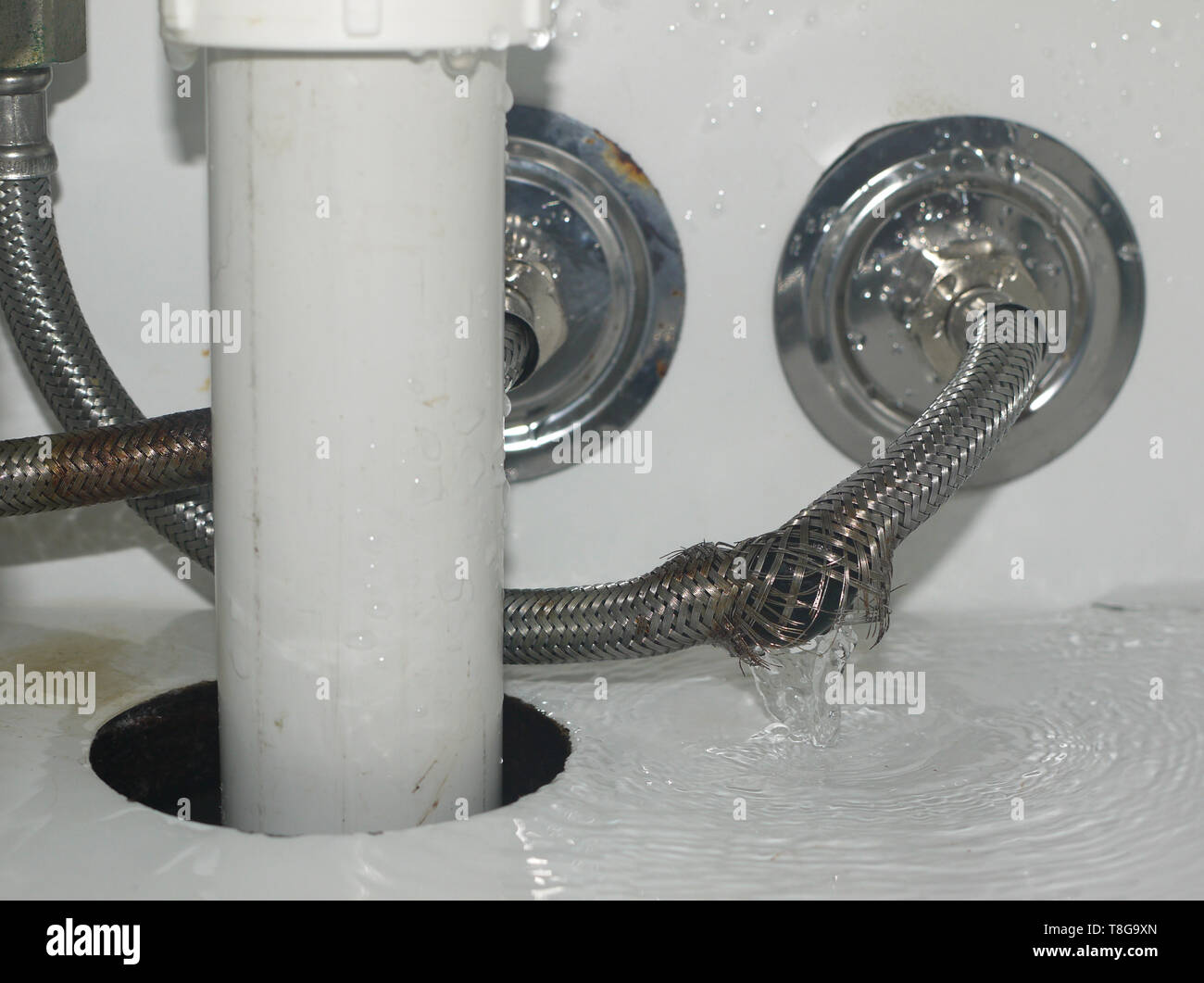 Acqua si riversa fuori di rottura tubo flessibile metallico nella stanza da bagno Foto Stock