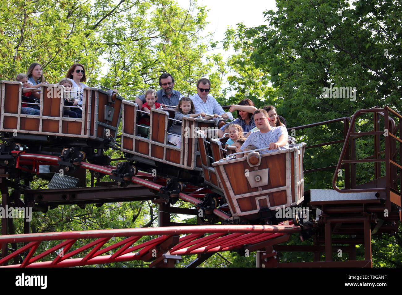 Mosca, Russia - Maggio 2019: persone di cavalcare un roller coaster in un parco divertimenti. Genitori felici con i vostri bambini si divertono nel parco Sokolniki, vacanza in famiglia Foto Stock